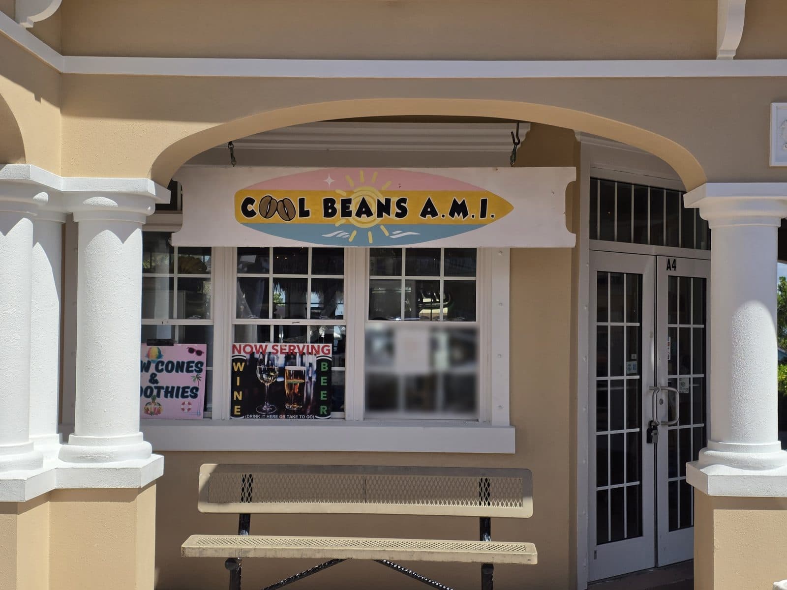 The Cool Beans A.M.I. surfboard sign over the window, with a Now Serving wine and beer card