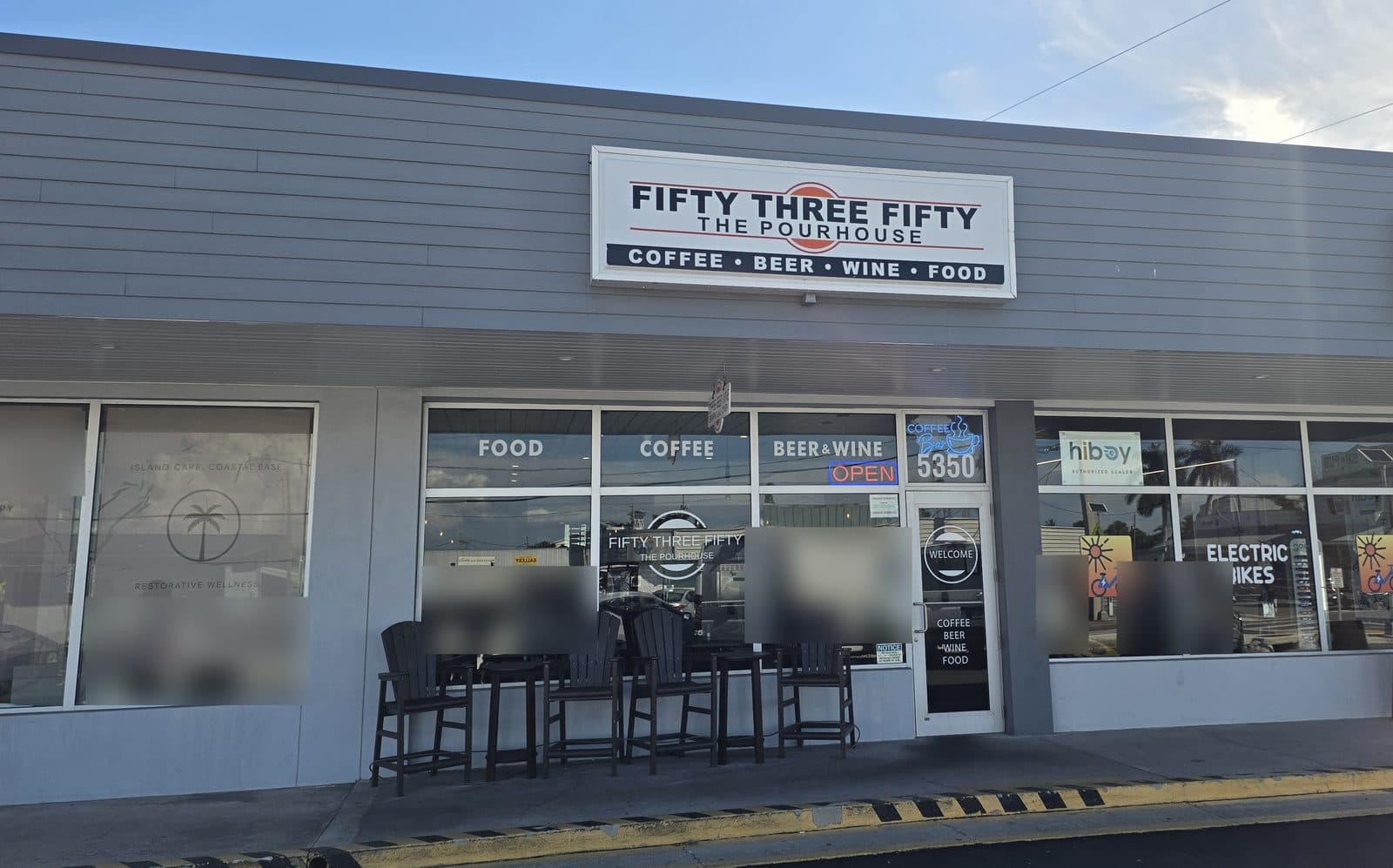 The Fifty Three Fifty The Pourhouse sign, Coffee, Beer, Wine, Food, over a glass storefront with dark porch chairs out front