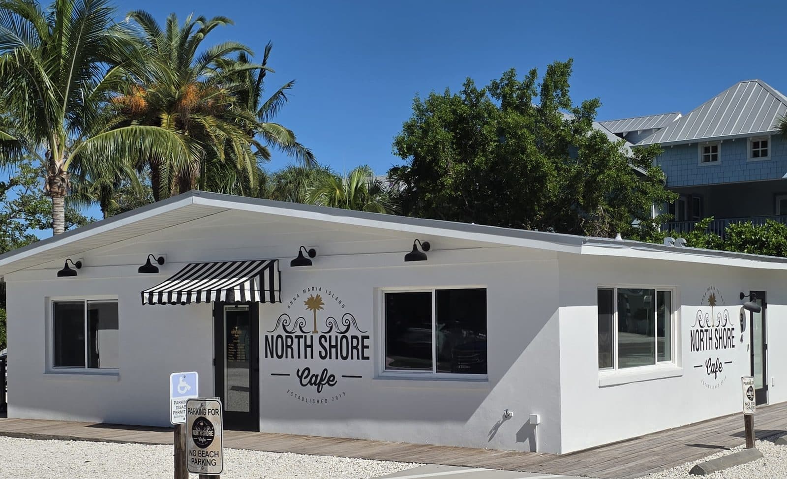 North Shore Cafe, a white cottage on Pine Ave with a black and white striped awning