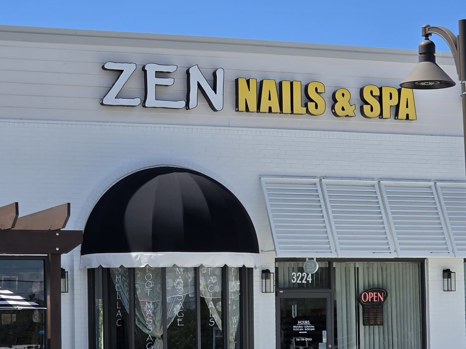 The yellow and white Zen Nails & Spa sign over a black awning